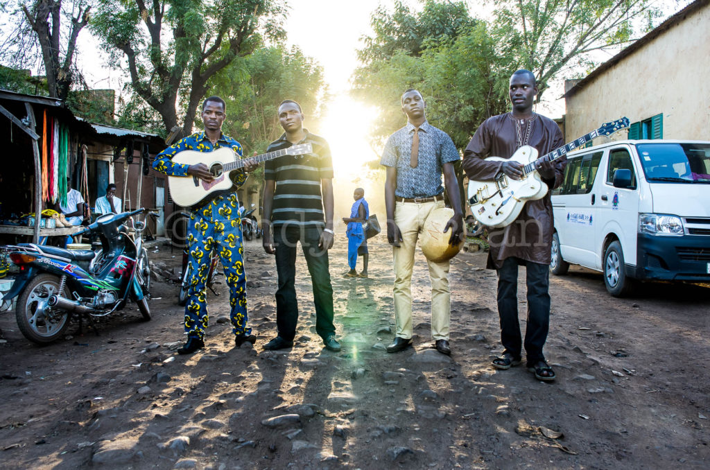 Songhoy Blues in Laffiabougou with girl looking back at them. 2014 (L-R Oumar, Ali, Nat, Garba). Photo: Andy Morgan